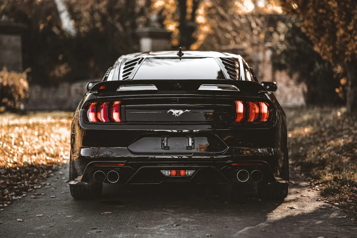 Crni Ford Mustang straga, sjaj tamnog laka u jesenskom svjetlu