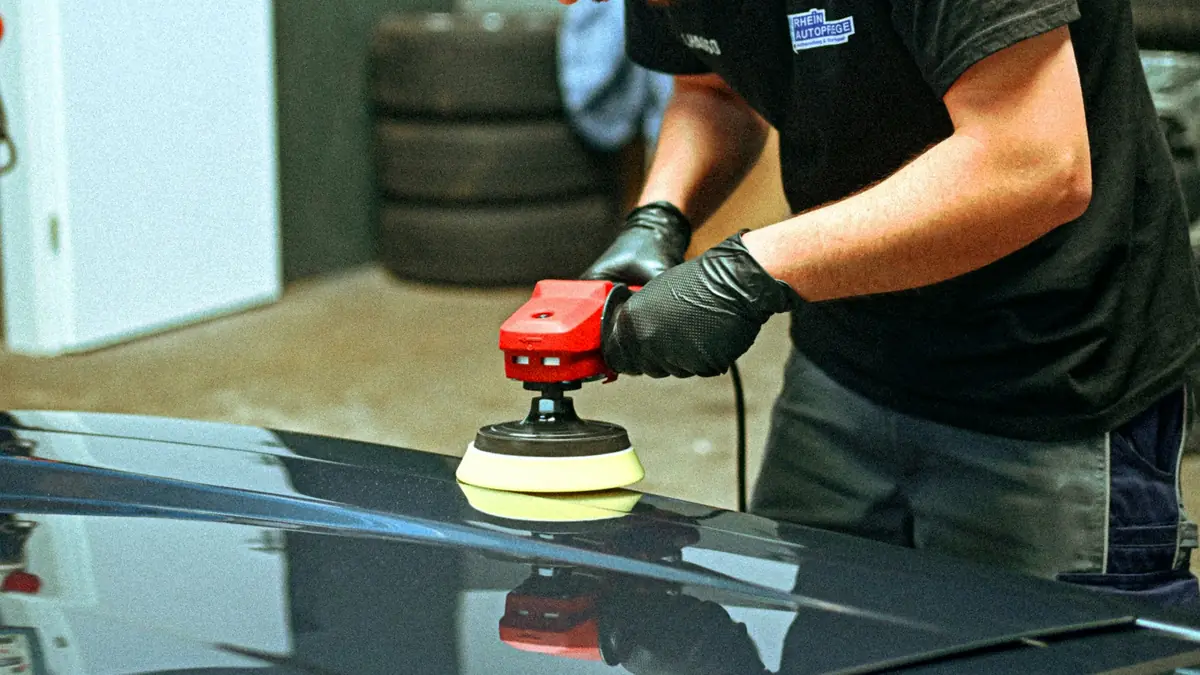 Detailer polirkom obrađuje haubu plavog automobila